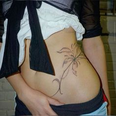 a woman's stomach with a tattoo on the side and an arm around her waist