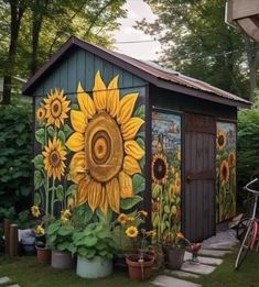 a garden shed with sunflowers painted on it's side and a bicycle parked in front