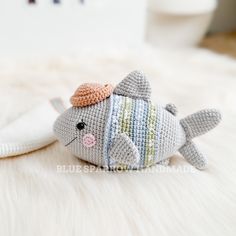 a crocheted stuffed fish with a hat on it's head sitting next to a white pillow