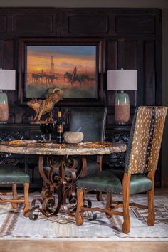 a dining room table with two chairs and a painting on the wall behind it,