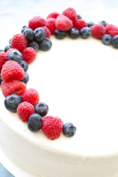 a white cake topped with berries and blueberries