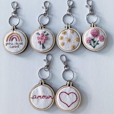 six embroidered keychains with different designs on them, each featuring a rainbow and flowers