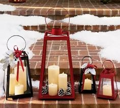 three red lanterns with white candles are sitting on the steps in front of some snow