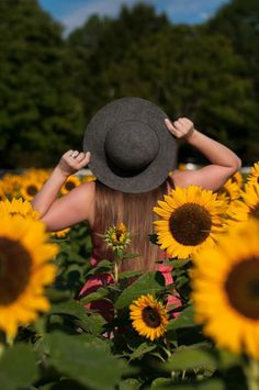 a woman in a sunflower field with her back to the camera