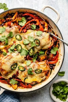 a skillet filled with chicken and vegetables covered in cheese, sauce, and cilantro