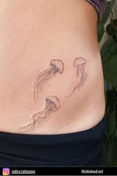 a woman's stomach with two jellyfish tattoos on it