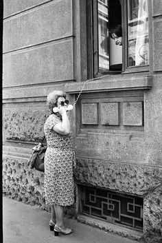 an old photo of a woman talking on her cell phone in front of a building