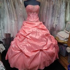 a pink dress sitting on top of a mannequin in front of some dresses