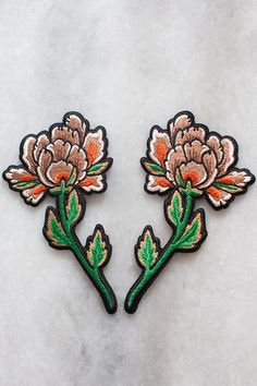 two embroidered flowers sitting on top of a white surface