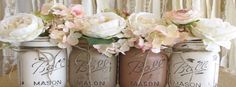 four mason jars with flowers in them sitting on a table