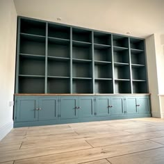 an empty room with blue bookcases and wood flooring on the side wall