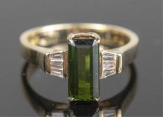 an emerald and diamond ring with two baguets