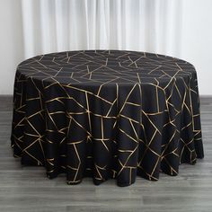 a black table with gold lines on it and a white curtain in the back ground