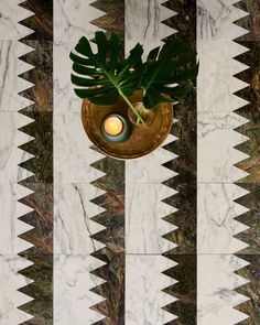 a vase with a candle on top of it sitting next to a marble wall and floor