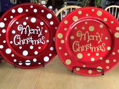 two red plates with merry christmas designs on them sitting on a table next to each other