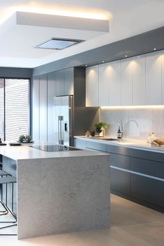 a modern kitchen with marble counter tops and stainless steel appliances, along with an island in the middle