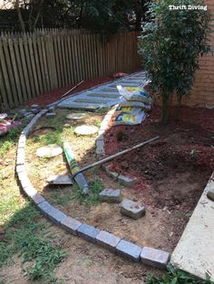 a garden with rocks and landscaping supplies in the ground next to a fenced area