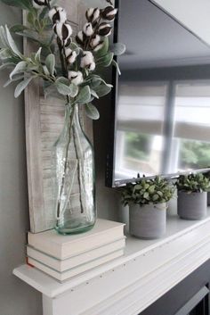 a vase filled with flowers sitting on top of a white mantle next to a mirror