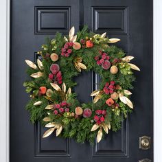 a christmas wreath on the front door of a house with red berries and greenery