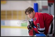 a young man in red and white jersey holding a hockey glove on his left hand