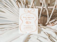 a white card with an orange bow on it next to some palm fronds