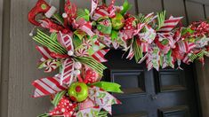 a christmas wreath with candy canes and bows hanging on the front door for holiday decor