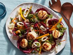 a white plate topped with scallops and veggies next to silverware