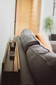 a remote control sitting on top of a couch next to a glass filled with liquid