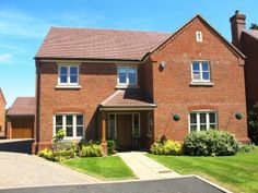 a large brick house sitting on top of a lush green field next to a road