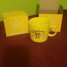 a yellow coffee mug sitting on top of a table next to a box with an image of a teddy bear