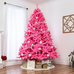 a pink christmas tree with presents under it