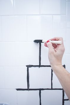 a person is drawing on the wall with black and white squares in front of them