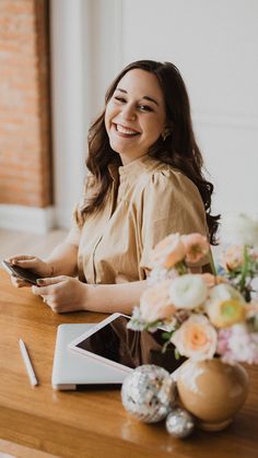 a woman sitting at a table holding a cell phone