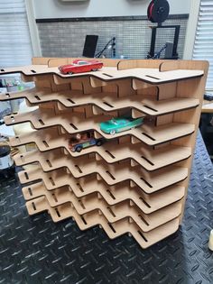 a shelf made out of plywood with toy cars on the top and bottom shelves