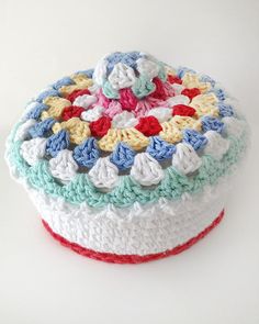 a multicolored crocheted cake sitting on top of a white table