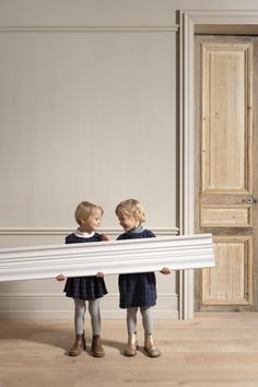 two young children standing next to each other holding a large piece of white material in their hands