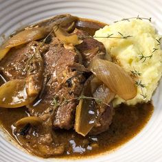 a white plate topped with mashed potatoes and beef