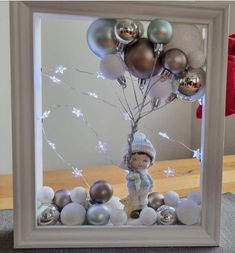 a photo frame with ornaments and a baby holding a bunch of balloons in the shape of a tree