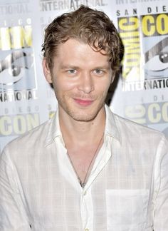 a young man is posing for the camera at a press room event with his hands in his pockets