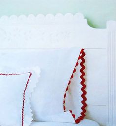 a white bed with red trim and pillows