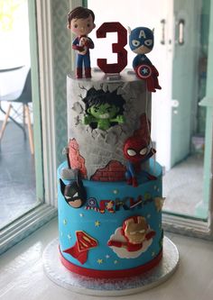 a three tiered birthday cake with the number 3 and superheros on it's side