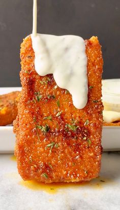 a piece of deep fried breaded food with sauce drizzled on top