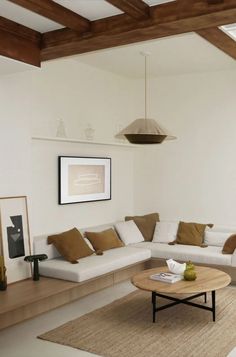 a living room with white couches and brown pillows on the floor, along with a coffee table