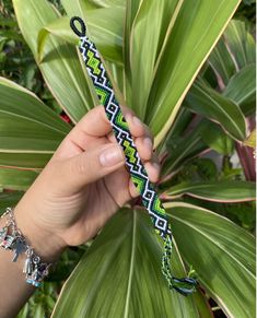 a person holding onto a green and black bracelet