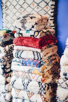 a pile of rugs stacked on top of each other in front of a blue wall