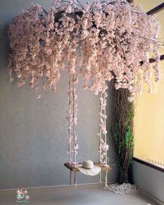 a room filled with lots of pink flowers hanging from it's ceiling next to a window