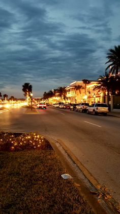 the street is lined with lights and palm trees