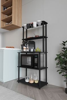 a black microwave oven sitting on top of a shelf next to a potted plant