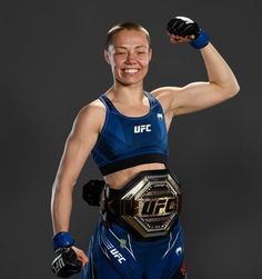 a female wrestler posing with her arms in the air and holding two boxing gloves over her shoulder