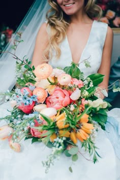 a woman in a wedding dress holding a bouquet of flowers and smiling at the camera